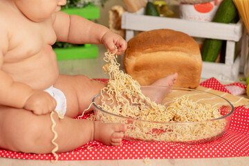 close up of a toddler's feet and hands touching spaghetti on a plate in the kitchen