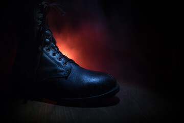 War concept. Old military shoe in a dark toned foggy background. Creative concept of conflict...