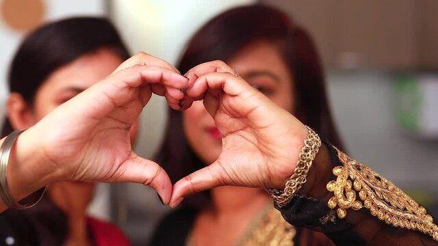 Valentine's Day concept indian women make with fingers heart shape smile look at camera through symbol