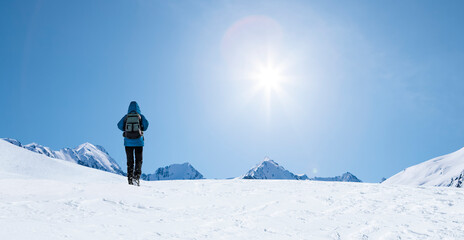 Fototapeta na wymiar Person mit Blaue Jacke wandert im Schnee in den Bergen