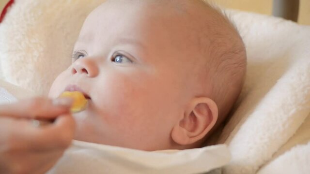 Cute baby eats from a spoon mom feeds, food, nutrition, childhood concepts