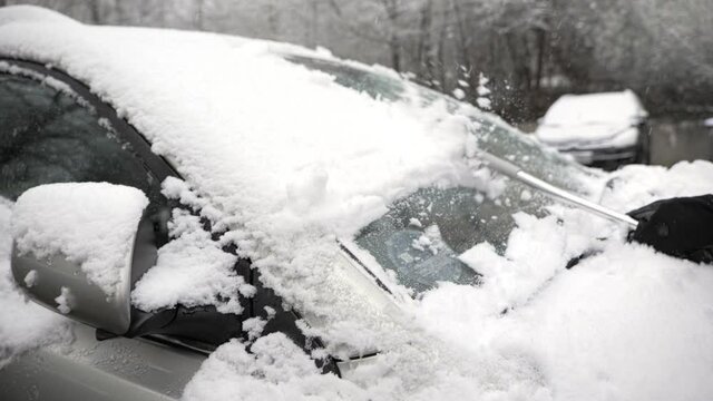 Brushing snow off the windshield of a car on a cold winter day, slow motion footage
