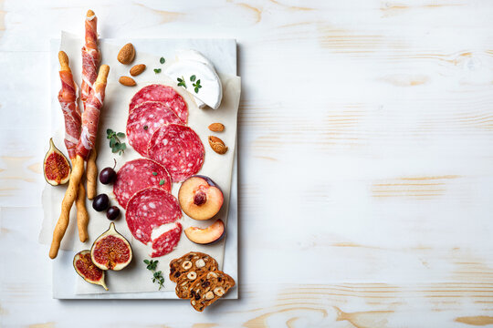 Appetizers table with italian antipasti snacks. Brushetta or authentic traditional spanish tapas set, cheese and meat variety board over wooden background. Top view, flat lay