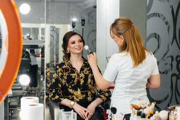 In a beautiful, modern beauty salon, a professional makeup stylist makes makeup for a young girl. Beauty, and fashion