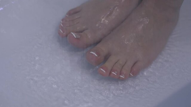 beautiful women's feet under water in the shower, skin care