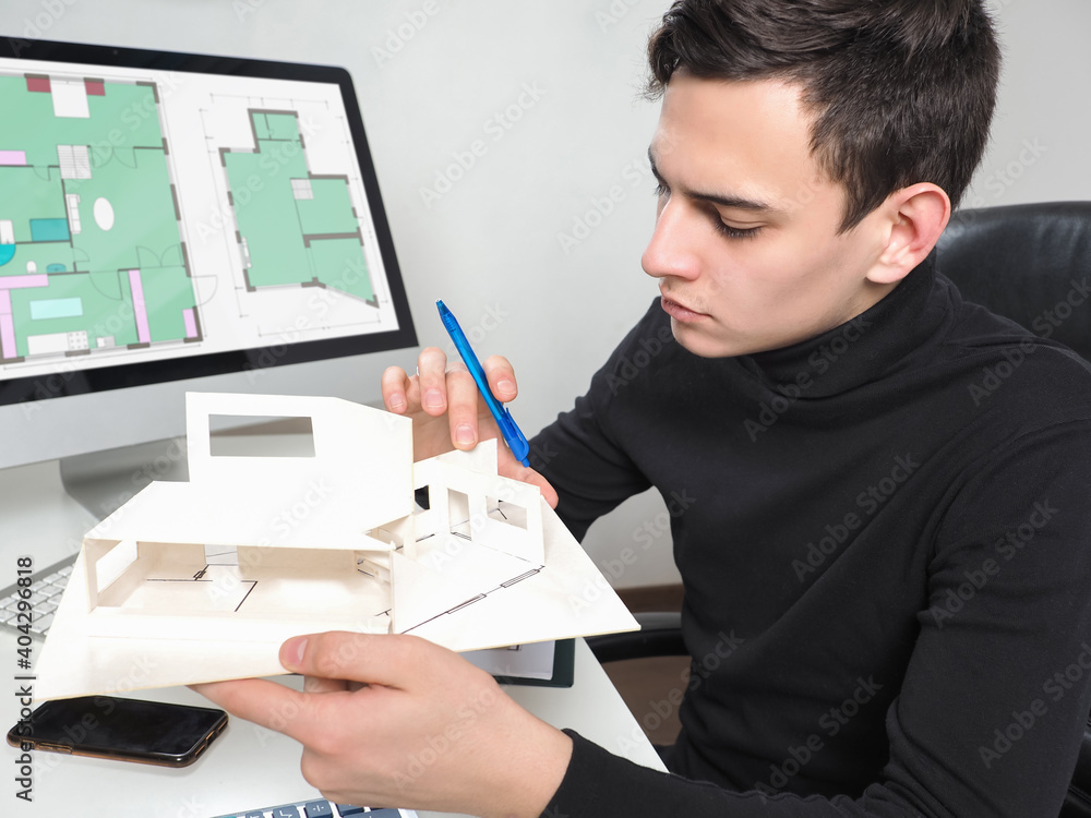Aufkleber architect student makes miniature madele at home. architectural drawings on his computer screen. arc