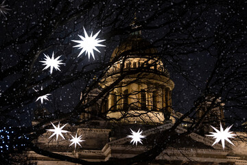 Glowing Christmas stars and cathedral in the background. Shadows of trees on a winter night