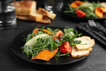 Delicious vegetable salad with microgreen served on black table
