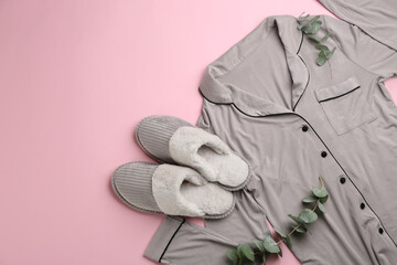 Pair of slippers, pajamas and eucalyptus branches on pink background, flat lay. Comfortable home...