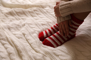 Woman in warm socks on knitted blanket, closeup. Space for text