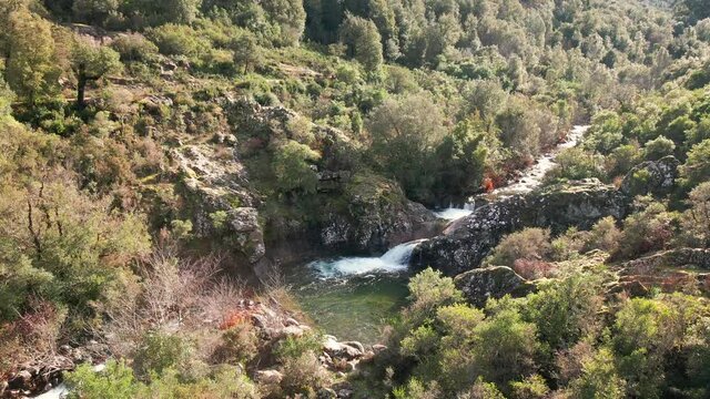 Aerial view of a mountain stream cascading into a clear pool at Pirio in Corsica
