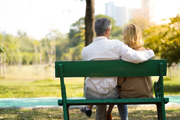Fototapeta premium Lovely mature senior couple sitting on bench together at park with happy relax and enjoy retirement lifestyle