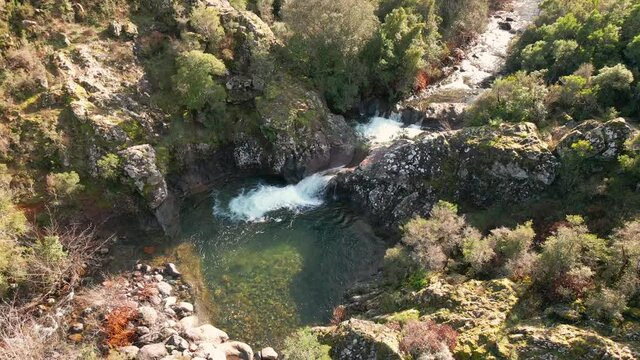Aerial view of a mountain stream cascading into a clear pool at Pirio in Corsica