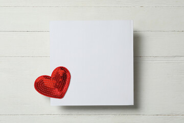 Blank card and decorative heart on white wooden background, top view with space for text. Valentine's Day celebration