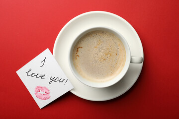 Obraz na płótnie Canvas Paper with words I Love You and coffee on red background, flat lay