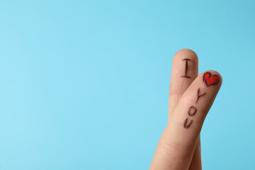 Fingers with phrase I Love You on light blue background