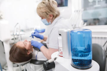 Selective focus on modern dental treatment device, professional dentist working with patient on background