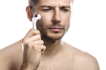 Young handsome man is  using derma roller for beard growth