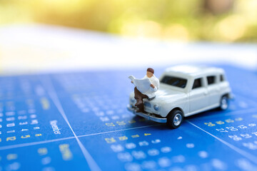 Miniature people: Businessman reading on car and calendar, education or business concept.