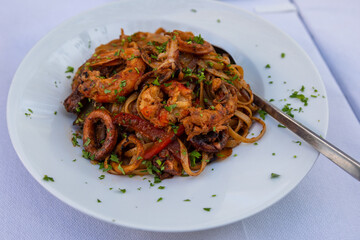 Colorful spaghetti with seafood on white plate.