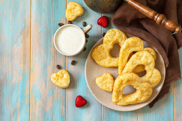 Breakfast for valentine's day or mother's day concept. Curd cheese pastries and a cup of cappuccino coffee on a rustic table. Top view flat lay. Copy space.