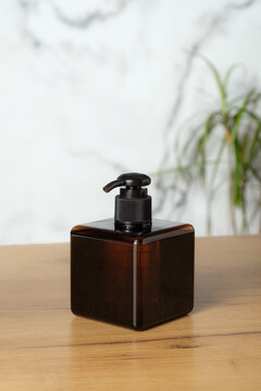 Square amber glass pump bottle mockup on table in bathroom. Elegant soap dispenser packaging design.