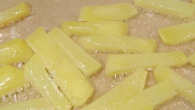 Close up of frying potatoes in hot boiling oil. Homemade french fries, fried in oil in a pan, the camera passes by the potato