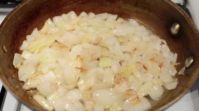 Onions are fried in a frying pan in oil.