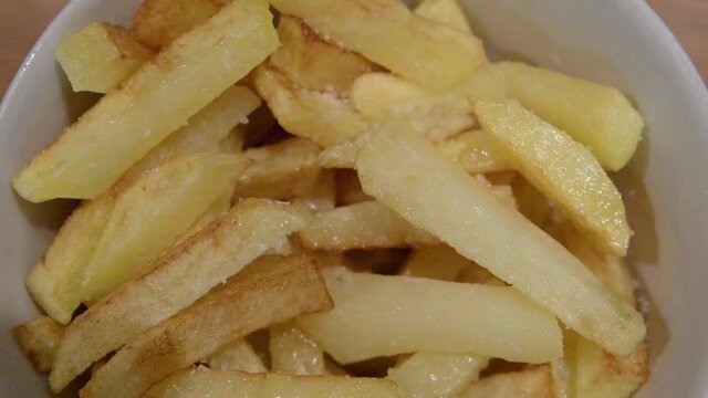 Close up of frying potatoes in hot boiling oil. Homemade french fries, fried in oil in a pan, the camera passes by the potato