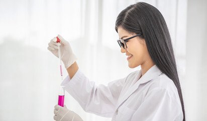 Young Asian scientist woman holding and looking at the chemical flasks in the laboratory	
