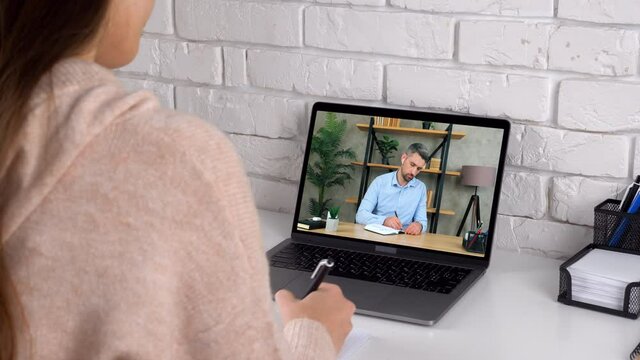 Businesswoman and businessman managers at home office work together communication remote online conference video call chat laptop computer webcam writes information in notebook, quarantine pandemic