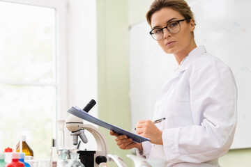 Woman scientist writing a report in a laboratory during research