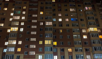 Facade of an old apartment building with balconies at night time. City scene at night, windows lights, background image.
