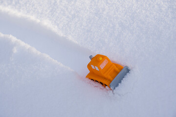 Toy snow plow in winter landscape. Road safety concept, street cleaning work, transportation in bad weather. - 404309849