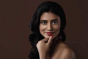 Indian woman with beautiful makeup and hairstyle on brown background