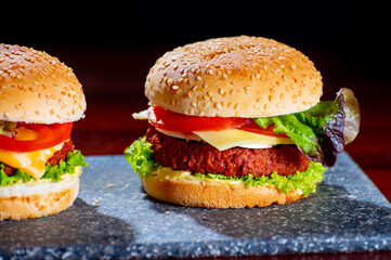 Tasty vegetarian food, homemade cheeseburgers made from plant based soya meat with cheese, onion, green lettuce and tomatoes