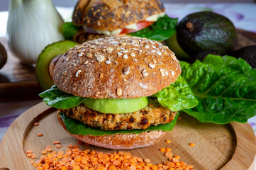 Tasty vegetarian healthy food, homemade burgers made from orange lentils legumes with green lettuce and fresh ripe avocado