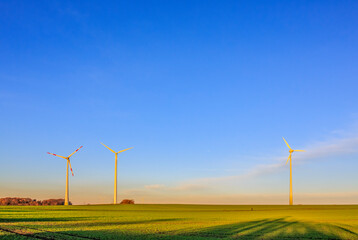 Windräder im Sonnenlicht vor blauem Himmel