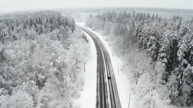 Aerial view of a car on road in winter snow covered forest. Winter landscape with Snow covered forest background.