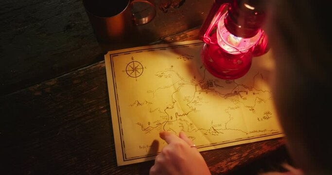 Top view of a woman pointing at the map with her forefinger. Female traveller holds red kerosene lamp. High quality 4k footage
