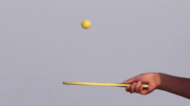 Guys playing matkot at the beach with a boy's hand handling a racket.