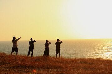 Editorial usage. Group of people do tai-chi training on the hill by the ocean on sunset time,...