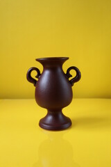 brown amphora vase with handles on a yellow background copyspace
