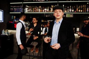 Stylish arab man against group of handsome retro well-dressed guys gangsters spend time at club, drinking on bar counter. Multiethnic male bachelor mafia party in restaurant.
