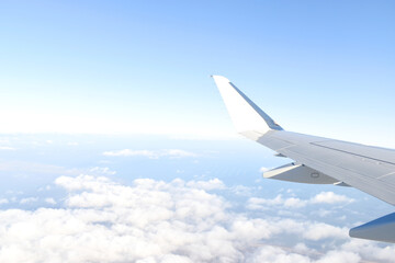 Fototapeta na wymiar Beautiful horizon blue sky with white wing of airplane fiying above white clouds. View from airplane window