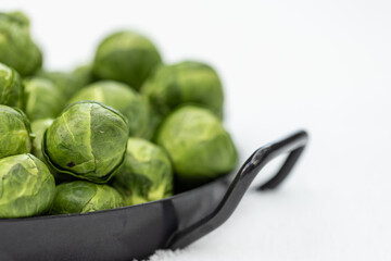 grüner Rosenkohl in einer Pfanne auf Schnee im Winter