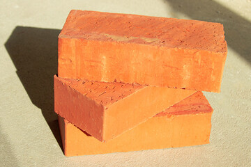 Three red bricks on the floor in sunlight
