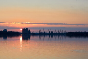 Fototapeta na wymiar View over the Danube river at port cranes at winter sunrise