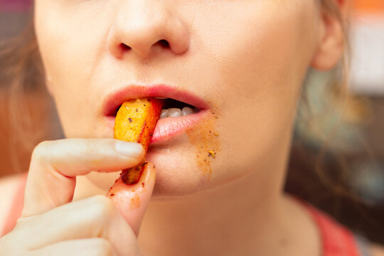 Woman putting french fries in her mouth and taking a bite, messy around the mouth 