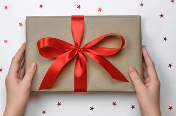 Foto auf Acrylglas Hände, die verpackte Geschenkbox mit rotem Band als Geschenk zum Feiern halten. © Albert Ziganshin